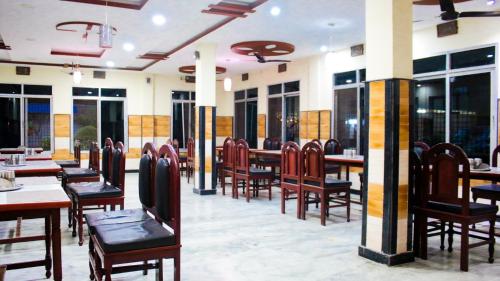 尼泊尔根杰Hotel Pahuna Ghar的餐厅设有木桌、椅子和窗户。