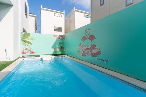恩纳グランディオーソ沖縄プールヴィラ恩納７的一座墙上壁画建筑前的游泳池