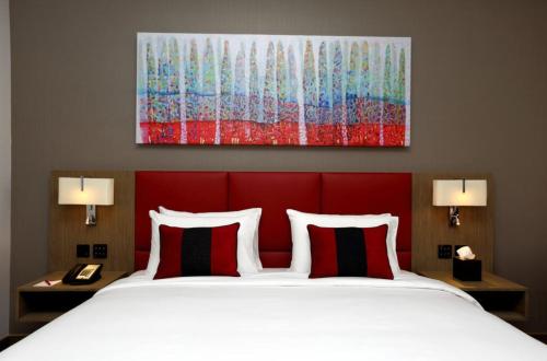 马斯喀特Ramada Encore by Wyndham Muscat Al-Ghubra的一间卧室配有一张带红色床头板的床和两盏灯。