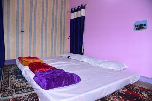 迈索尔S & H Stay Home的一张白色大床,配有色彩缤纷的床单和枕头