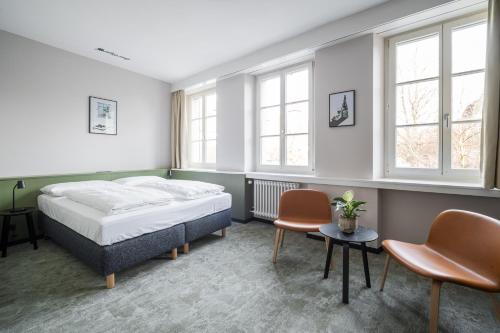卢塞恩Hotel Goldener Stern - contactless check-in的一间卧室配有一张床、两把椅子和窗户
