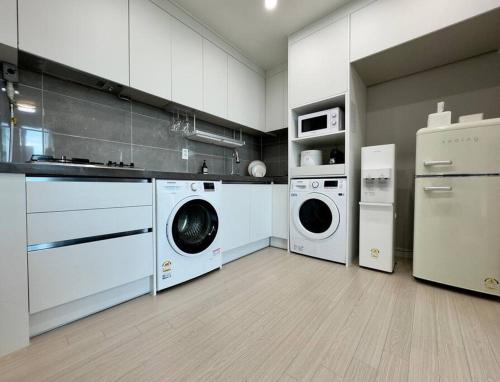 大田Eunhasu D&M Residence Cheongcho 4的厨房配有白色橱柜、洗衣机和烘干机