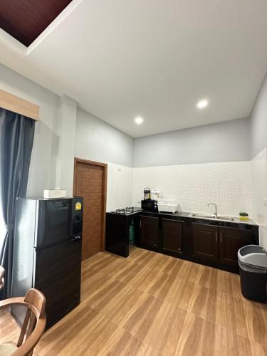 班奥南矛Mega Pool Villa,Aonang的厨房铺有木地板,配有黑色冰箱。