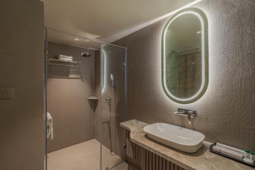 拉杰果德Phoenix Resort的浴室配有盥洗盆和带镜子的淋浴