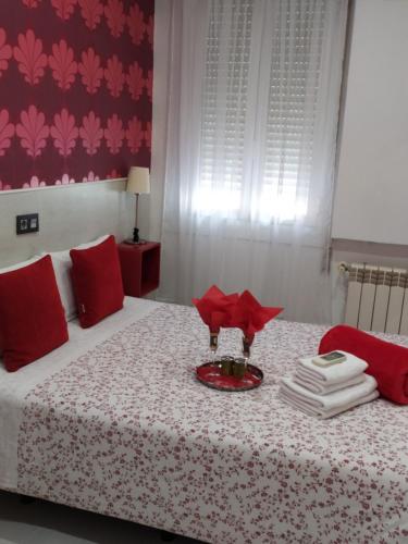 马德里马德里客栈旅馆的一间卧室配有一张带红色枕头和盘子的床
