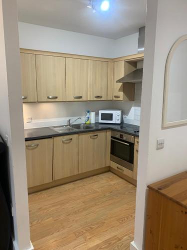 切舍姆Aspect apartments的厨房配有木制橱柜、水槽和微波炉