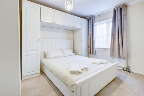 BattlesbridgePass the Keys Spacious 4-Bedroom Home in Benfleet的卧室配有白色的床和2条毛巾