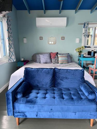 乌蒂拉Dockside Utila Ocean front suites的一张蓝色的沙发,位于带床的房间
