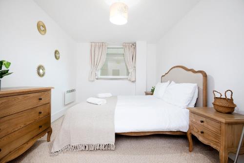 伦敦2 Bed 2 Bath Close to Big Ben的卧室配有白色的床和木制梳妆台。