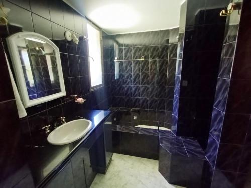圣卡洛斯-德巴里洛切hermosa casa a una cuadra del lago的黑色瓷砖浴室设有水槽和淋浴
