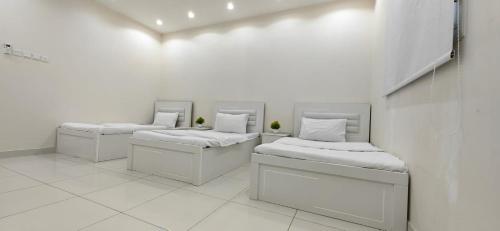 雷伊斯اوس الحجاز的白色墙壁的客房内的三张床