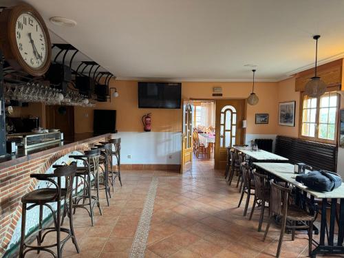 Alba de los CardañosHotel Pico Espiguete的餐厅设有桌椅和墙上的时钟