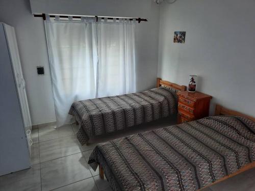 内科切阿Necochea-Casa para hasta 4 personas!的一间卧室设有两张床、一个梳妆台和窗户。