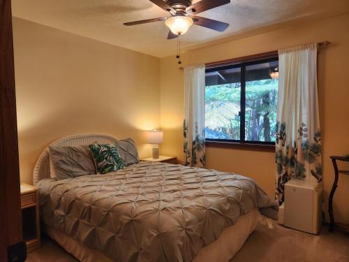 沃尔卡诺Hale Mauna Loa Upper Level with shared Hot Tub的一间卧室配有一张带吊扇和窗户的床。
