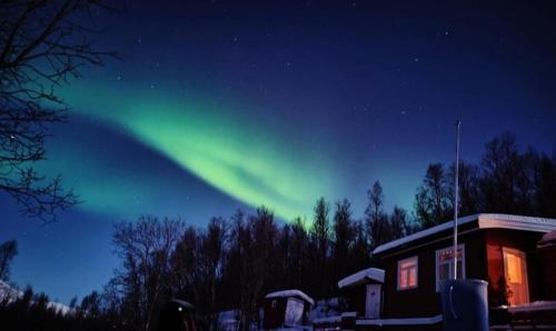 SvensbyCozy and spacious cabin的天空中的一个极光,就在房子旁边