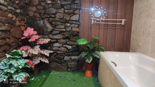 珍南海滩Villa Dalam Laut 580的浴室设有石墙、浴缸和植物