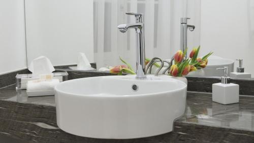 格拉茨City De Lights的浴室设有白色水槽和花朵,位于柜台上