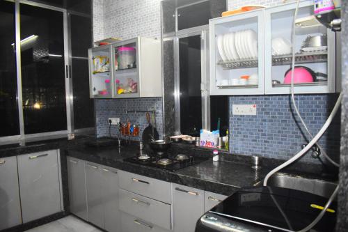 孟买Prince Solo Hostel的厨房配有白色橱柜和黑色台面