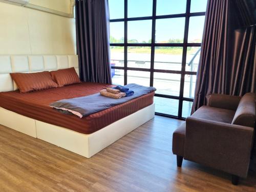 แพรุ่งธารา ไชโย (Rungtara Houseboats)的卧室配有床、椅子和窗户。