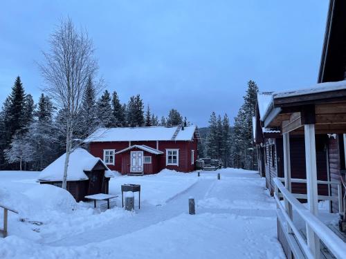 KoskullskulleSkogen-Lodge的一座红房子,在建筑物旁边,地上有雪