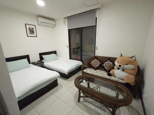 台北伍貓喵舍Cat5mewomeow的一间设有两张床的房间,一张沙发上配有泰迪熊