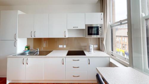 诺丁汉Flat 302 Centre Nottingham的厨房配有白色橱柜、水槽和窗户。