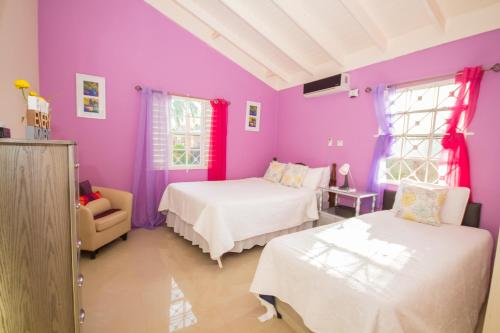 圣安斯贝Ocho Rios Drax Hall 1 Bedroom sleeps 1-3 persons的紫色的客房配有两张床和一把椅子