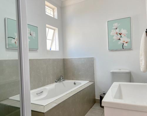 比勒陀利亚Amoris Guesthouse - In Brooklyn的白色的浴室设有浴缸和水槽。