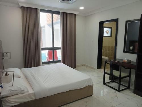 阿尔科兰Al Salam Resort的一间卧室配有一张床、一张书桌和一个窗户。