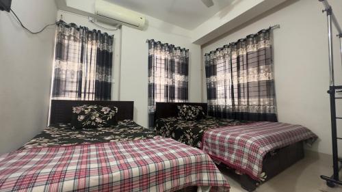 达卡Appayan Guest House (Baridhara)的一间卧室设有两张床和两个窗户。