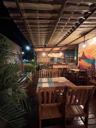 费尔南多 - 迪诺罗尼亚Coral azul Noronha的餐厅设有木桌和椅子,墙上挂有绘画作品