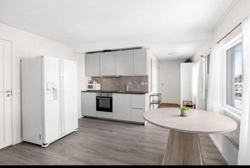Modern 2-bedroom apartment的白色的厨房配有桌子和白色冰箱