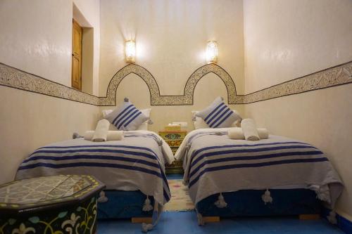 马拉喀什Flowers riad的一间卧室设有两张床,墙上设有一面镜子