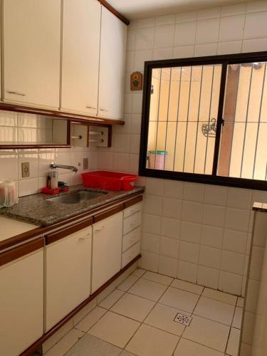 瓜拉派瑞APTO PRAIA DO MORRO, 02 QUARTOS C SUITE, WI-FI, GARAGEM, 1 ANDAR ESCADA.的小厨房配有白色橱柜和水槽