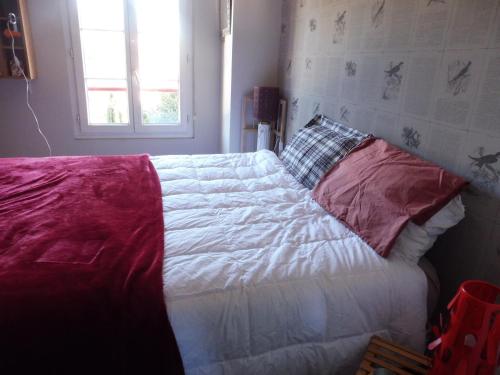 BillèreGure Doya的卧室内的一张带白色床单和红色枕头的床