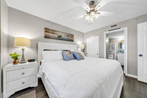 德斯坦Pelican Beach Resort Unit 1109的卧室配有白色的床和吊扇