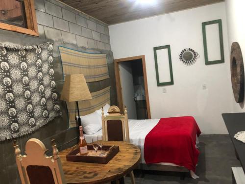 普腊亚罗萨Pousada Rosa Bonita的一间卧室配有一张床和一张桌子及一瓶葡萄酒