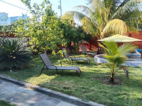 San Pedro MasahuatCasa para descanso familiar的院子里有三个公园长椅和一把雨伞