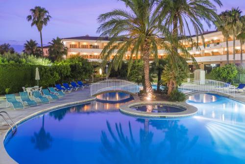 坎布里尔斯麦斯哥路酒店的一座棕榈树和椅子的度假游泳池以及一座建筑