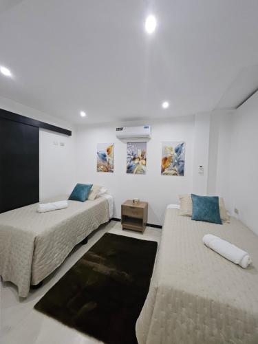 马查拉Urbanizacion privada "El Sol", Villa K2的白色客房的两张床,墙上挂有绘画作品