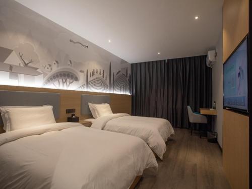 怀化尚客优连锁湖南怀化鹤城区高铁南站店的酒店客房设有两张床和一台平面电视。