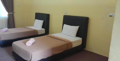 Kota BharuAlia Tiara River and Beach Resort的配有两张床的酒店客房中的两张床