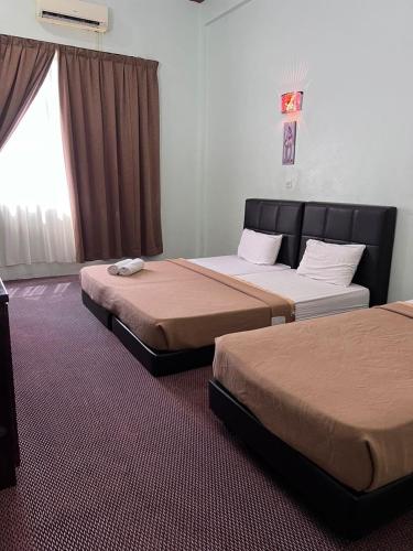 Kota BharuAlia Tiara River and Beach Resort的一间卧室设有两张床和窗户。