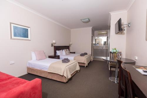 HighfieldsHighfields Motel Toowoomba的酒店客房设有两张床和一张桌子。