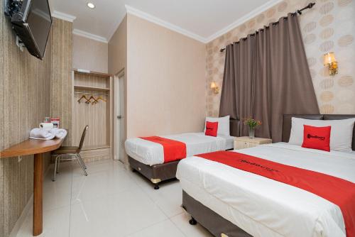 雅加达红门优质酒店 @ 范登巴拉特的酒店客房设有两张床、一张桌子和一台电视。