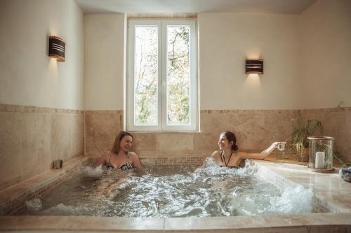 奥瑞阿卡杜佩里戈尔Cabane de La Mésange的两个妇女在带窗户的按摩浴缸内
