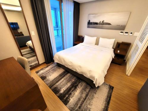 釜山W Residence Hotel的卧室设有一张白色大床和楼梯。