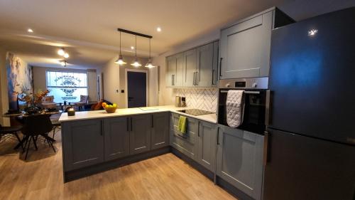 布莱顿霍夫Stylish 2 bed townhouse的厨房配有灰色橱柜和黑色冰箱