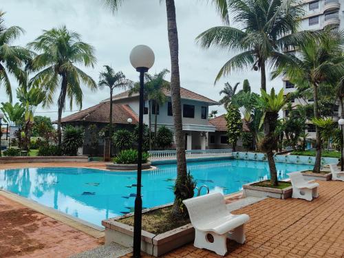 马六甲Klebang GX Homestay Resort Pool View P0804 with Netflix, TVBox and Games的一个带白色椅子和棕榈树的度假游泳池