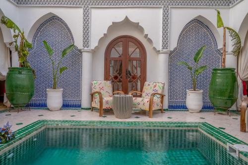马拉喀什Riad Ekla Boutique Hotel的一座带椅子和植物的别墅内的游泳池